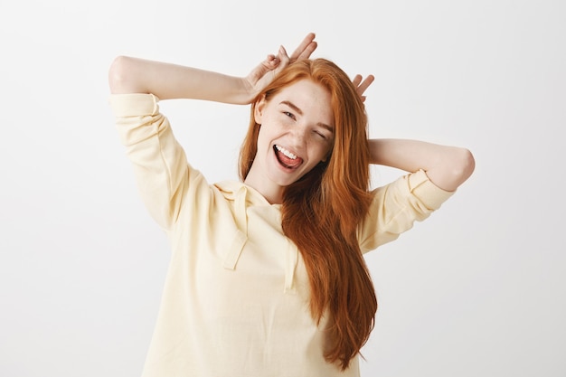 Chica pelirroja despreocupada divirtiéndose, sonriendo y guiñando un ojo