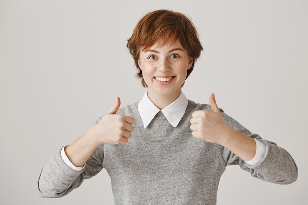 Foto gratuita chica pelirroja emocionada y satisfecha con corte de pelo corto posando contra la pared blanca