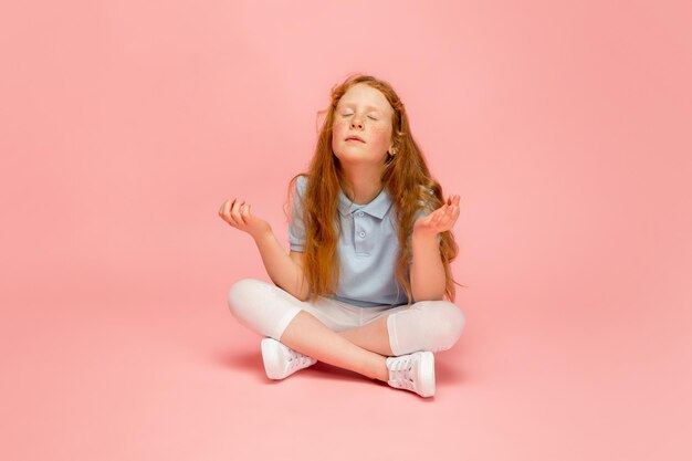 Chica pelirroja feliz aislada sobre fondo de estudio rosa Se ve feliz alegre sincero Copyspace Concepto de emociones de educación infantil