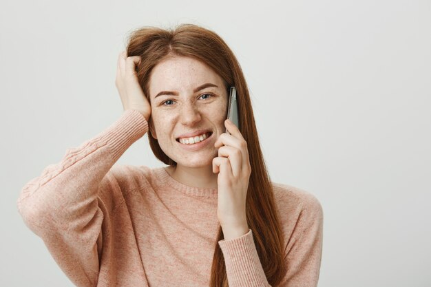 Chica pelirroja incómoda preocupada disculpándose en la conversación por teléfono móvil