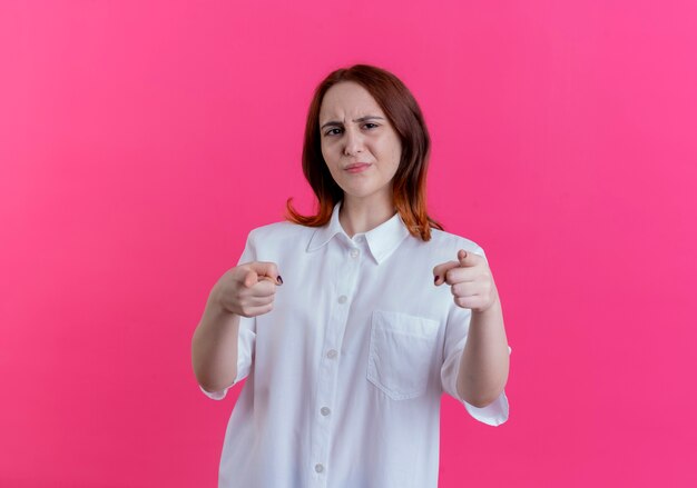 Chica pelirroja joven disgustada mostrando gesto aislado en rosa