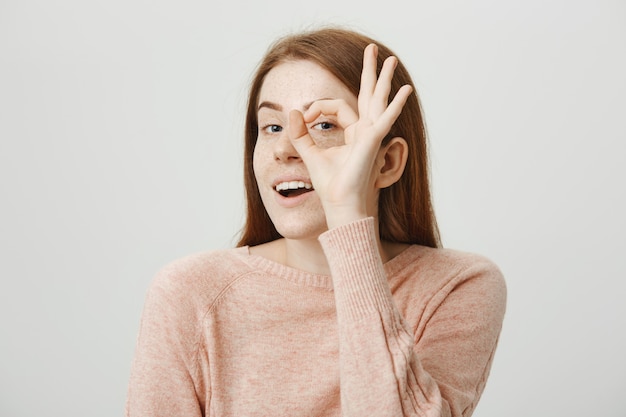 Chica pelirroja linda atractiva mostrando gesto bien sobre el ojo