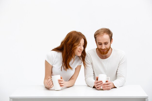 Chica pelirroja mira al hombre taza vacía