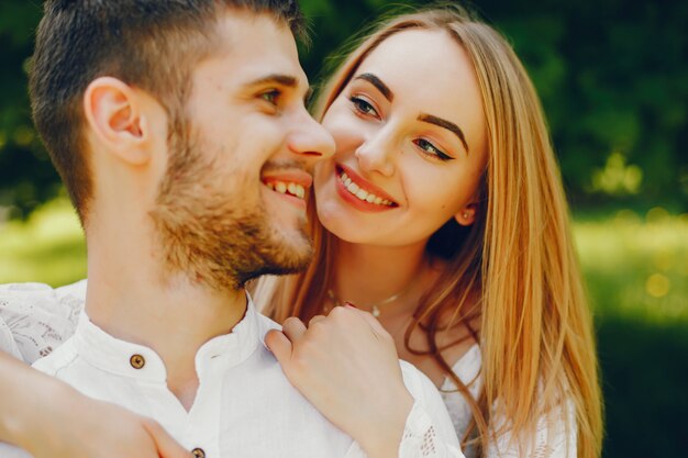 chica con pelo claro y un vestido blanco en un bosque soleado con su novio