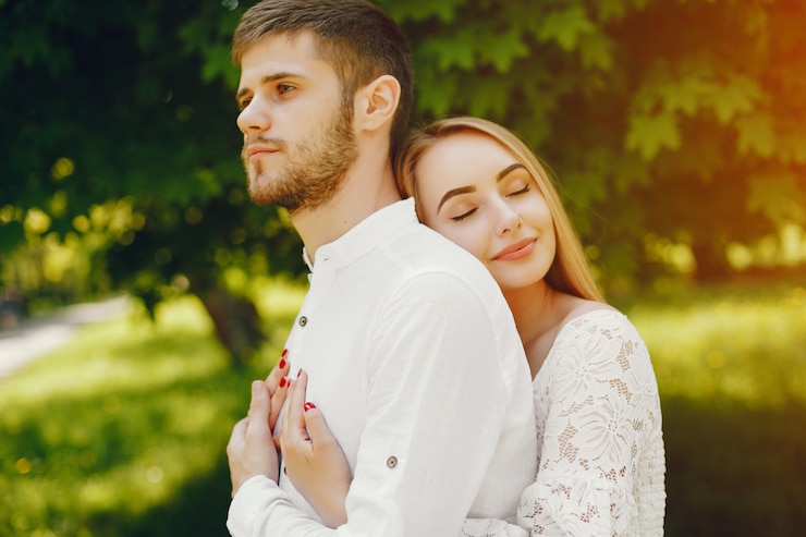 Foto gratuito chica con pelo claro y un vestido blanco en un bosque soleado con su novio