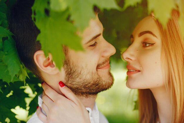 chica con pelo claro y un vestido blanco en un bosque soleado con su novio