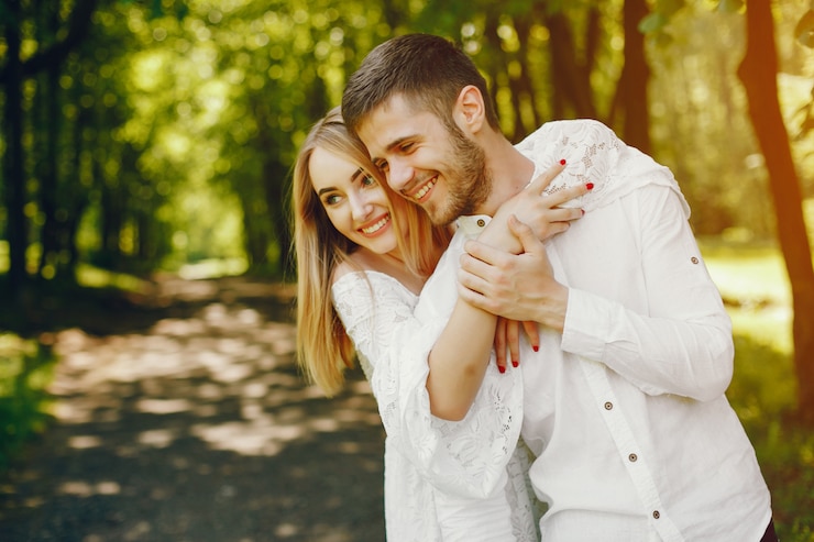 Foto gratuito chica con pelo claro y un vestido blanco está caminando en un bosque soleado con su novio
