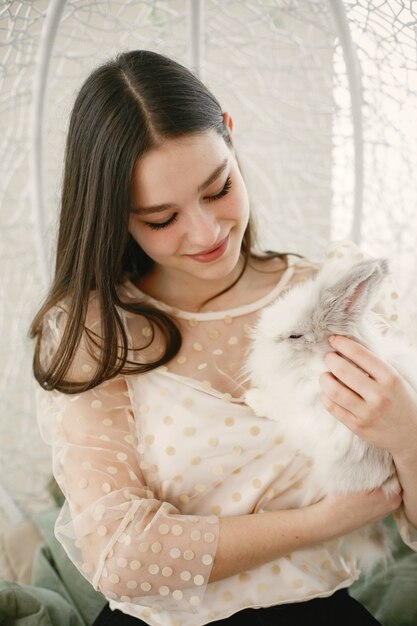 Chica de pelo largo. Conejo blanco en brazos de niña.