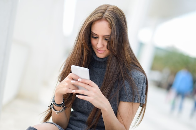 Chica con el pelo largo mandando mensajes con su móvil