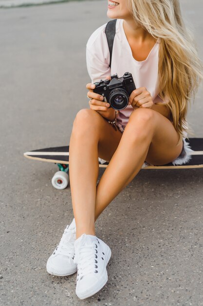 chica con el pelo largo con monopatín fotografiando en cámara. calle, deportes activos