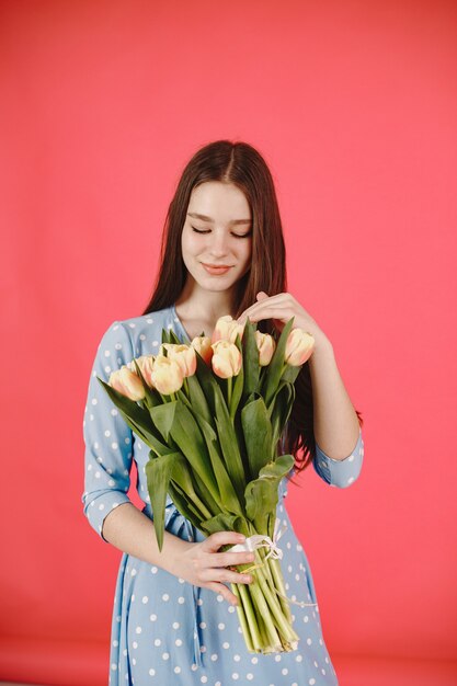 Chica de pelo largo. Mujer con un ramo de flores. Dama con un vestido azul.