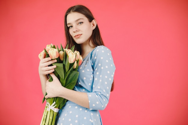 Chica de pelo largo. Mujer con un ramo de flores. Dama con un vestido azul.