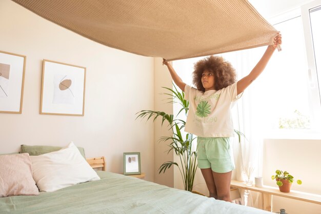 Chica con el pelo rizado haciendo la cama