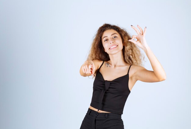 Chica con pelos rizados mostrando signo de mano positivo.