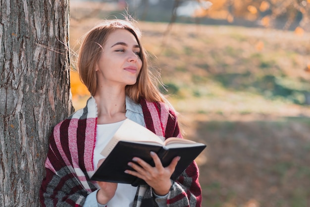 Foto gratuita chica pensante sosteniendo un cuaderno y mirando a otro lado