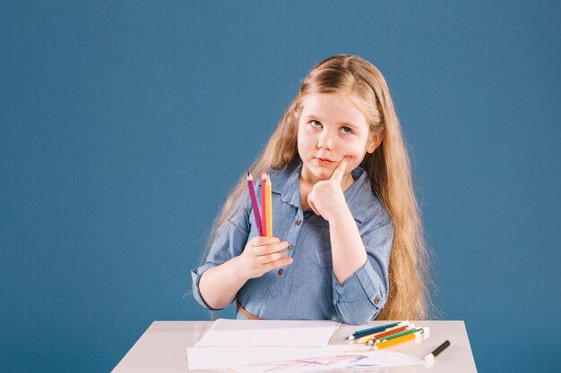 Chica pensativa dibujar en la mesa