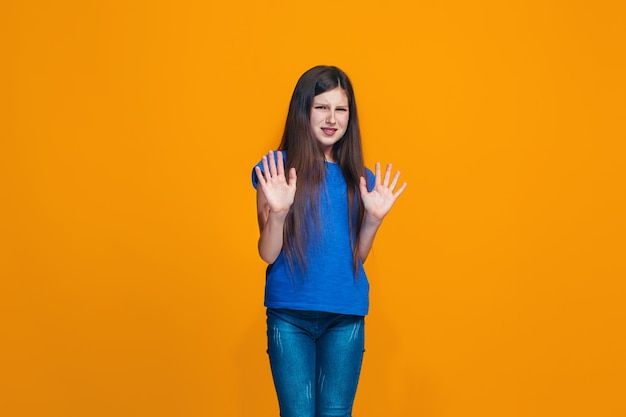 Chica pensativa dudosa rechazando algo contra la pared naranja