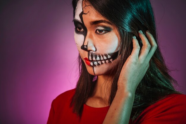Chica pensativa con makeup y máscara de halloween