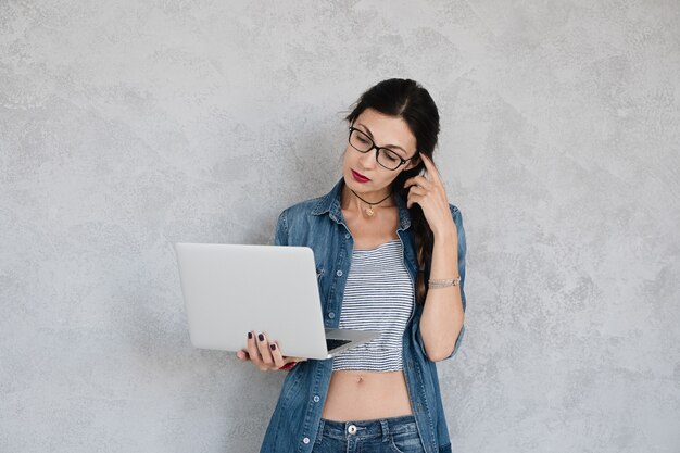 Chica pensativa mirando a una computadora portátil