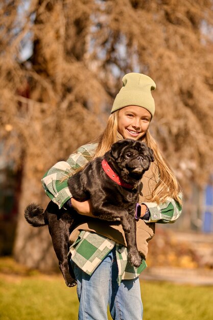 Chica con un perro. Bonita chica rubia sosteniendo a su perro y sonriendo