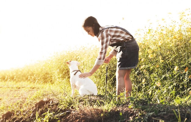 Chica con un perro en el campo de flores.