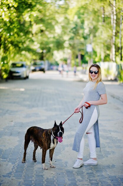Chica con perro pit bull terrier en un paseo