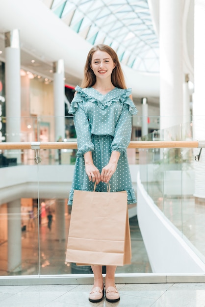 Chica de pie con bolsas de compras en el centro comercial