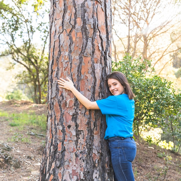 Chica de pie en el bosque y abrazando el árbol