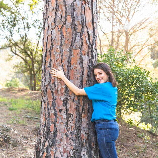 Chica de pie en el bosque y abrazando el árbol