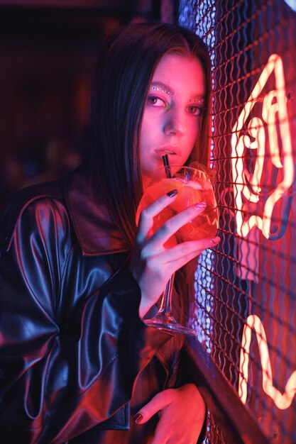 Chica de pie en un club nocturno con coloridas luces rojas de neón brillante