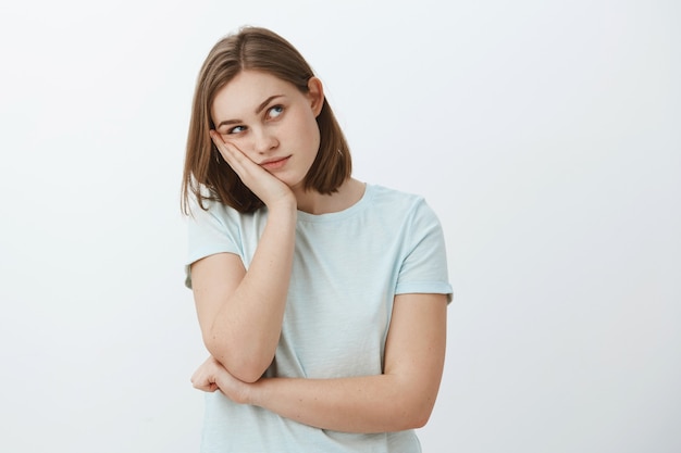 La chica piensa que la fiesta es una tontería. Aburrida joven mujer europea con corte de pelo corto y castaño con la cabeza apoyada en la palma mirando la esquina superior derecha pensando usando la imaginación para entretenerse mientras muere de aburrimiento