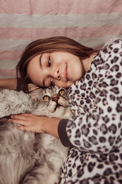 Chica en pijama y gato en la cama