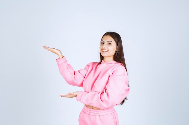 Chica en pijama rosa apuntando a algo a la izquierda