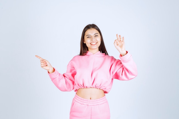 Chica en pijama rosa apuntando a algo a la izquierda