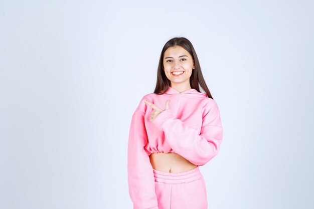 Chica en pijama rosa apuntando a algo a la izquierda