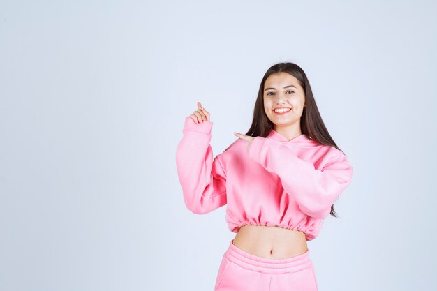 Chica en pijama rosa apuntando hacia arriba