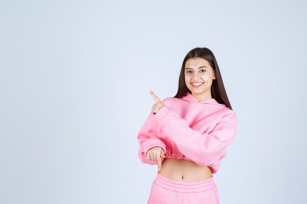 Chica en pijama rosa apuntando hacia el lado izquierdo