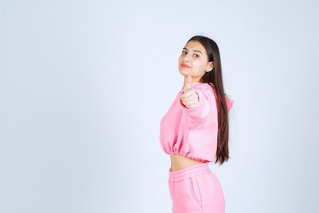 Chica en pijama rosa mostrando el pulgar hacia arriba