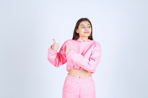Chica en pijama rosa mostrando el pulgar hacia arriba