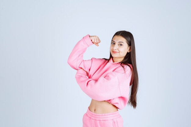 Chica en pijama rosa mostrando su puño y sintiéndose poderosa.