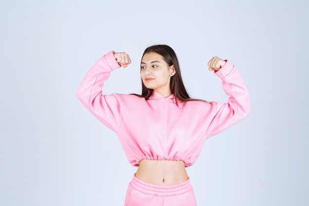 Chica en pijama rosa mostrando sus músculos del brazo