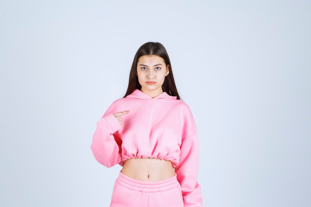 Foto gratuita chica en pijama rosa parece confundida e inexperta