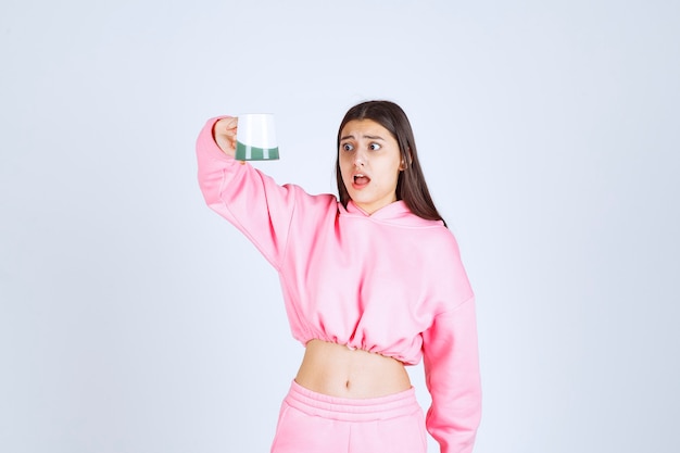 Chica en pijama rosa tomando una taza de café vacía y se decepciona.