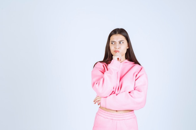 La chica en pijama rosa se ve confundida y pensativa.