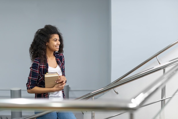 Chica con pila de libros subir escaleras