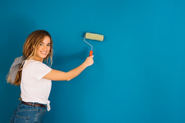 Chica pintando pared azul