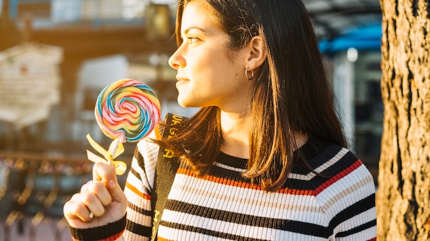 Foto gratuita chica con piruleta colorida iluminada por el sol