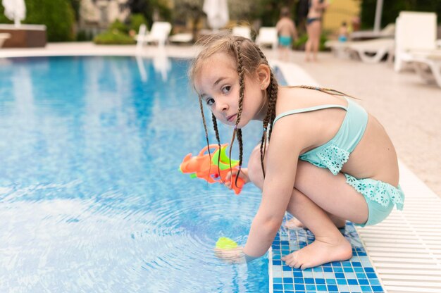 Chica con pistola de agua en la piscina