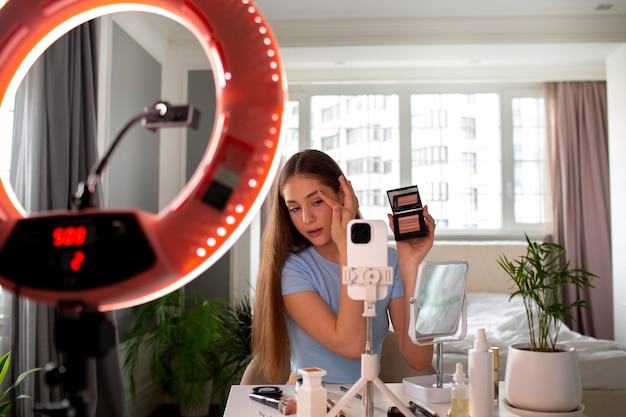 Foto gratuita chica de plano medio grabando su rutina de maquillaje.