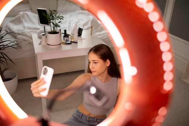 Chica de plano medio grabando su rutina de maquillaje.